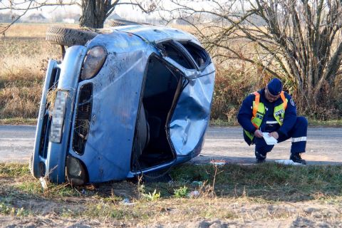 Rendőr helyszínel egy felborult autó mellett Kunszentmiklóson 2018. november 8-án. A jármű a kanyarban borult fel, vezetője az autó alá szorult és életét vesztette. A kocsi másik utasa könnyebben megsérült.