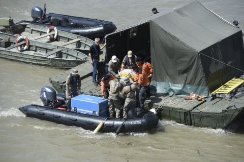A dél-koreai és a magyar mentőegység tagjai felszerelést pakolnak ki a kiépített keresőpontonra a hajóbalesetben elsüllyedt Hableány turistahajó közelében 2019. június 1-jén.