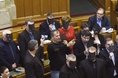 A DK, az MSZP és Párbeszéd képviselői a kulturális törvénycsomag szavazása közben tiltakozásul felállnak és fekete maszkot tartanak az arcuk elé az Országgyűlés plenáris ülésén 2019. december 11-én.