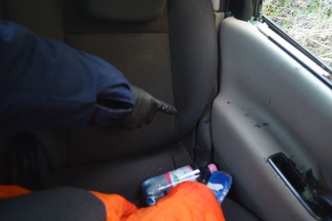 A rendőr mutatja, hogy nem használták a hátsó biztonsági övet az összetört autóban.