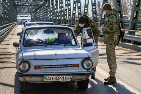 Védőmaszkot viselő ukrán határőrök mérik egy belépő gépkocsivezető testhőmérsékletét a Csaphoz közeli Tisza közúti határátkelőn, az ukrán-magyar határon 2020. február 25-én.