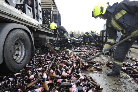 Tűzoltók takarítják fel és pakolják egy sörszállító kamion leborult rakományát az M0-ás autóútról az M4-es autópályára vezető felhajtónál Budapest határában 2020. február 27-én.