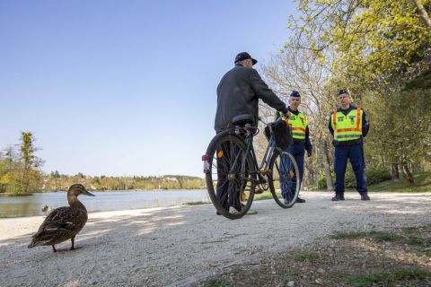 Járőröző rendőrök beszélgetnek egy férfival Szombathelyen, a Csónakázó-tó partján 2020. április 10-én.