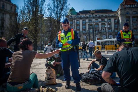 Rendőrök igazoltatnak egy csoportot a budapesti Szent Gellért téren 2020. április 8-án.