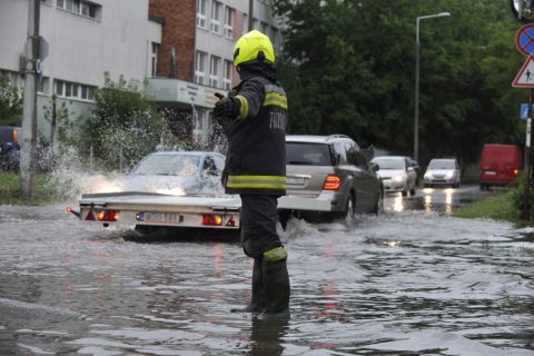 Tűzoltó irányítja a vihar után összegyűlt esővízben haladó járműveket a főváros X. kerületében, a Maglódi út és a Gitár utca kereszteződésénél 2020. június 14-én.