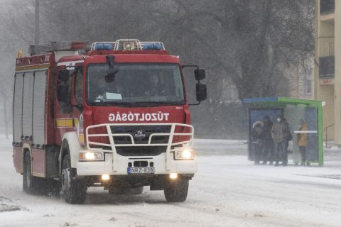 Tűzoltóautó és buszmegállóban várakozó utasok hóviharban Nyíregyházán, a Sóstói úton 2021. február 11-én.