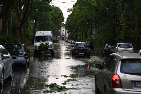 Autók haladnak a felhőszakadás után esővízzel elárasztott, letört faágakkal teli úton Budapesten, Wekerletelepen 2021. július 9-én.