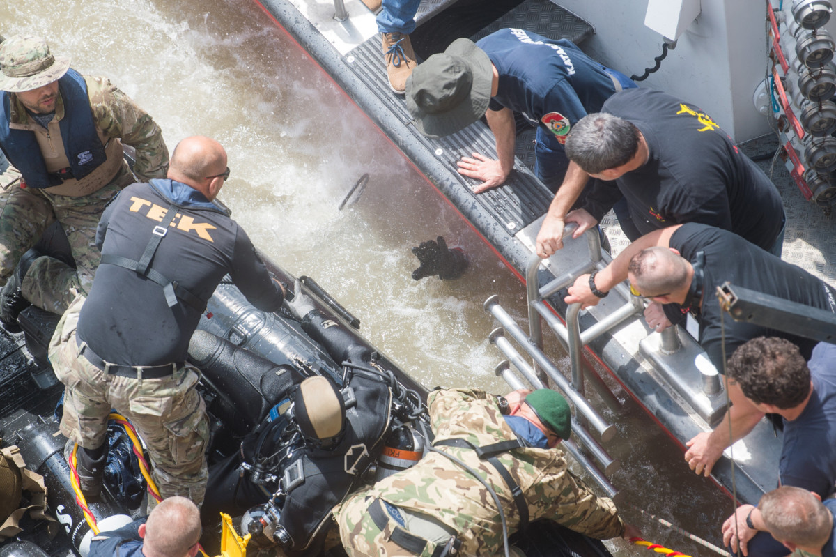 A roncsfeltáró munkálatokat végző búvárok egyike nyújtja ki kezét a vízből az őt kihúzni készülő társai felé a hajóbalesetben elsüllyedt Hableány turistahajó közelében, a Margit hídnál 2019. május 31-én.
