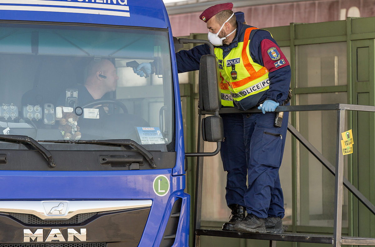Rendőr ellenőrzi egy kamionos hőmérsékletét Hegyeshalomnál, a határátkelőnél 2020. március 16-án.