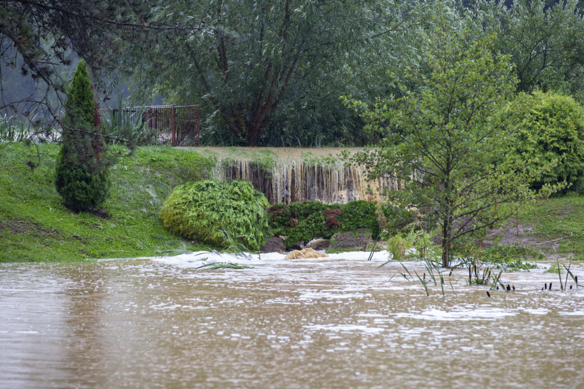 Víz folyik ki a nagy esőzés miatt megtelt tó gátjának teteje felett a Zala megyei Surdon 2020. július 25-én.