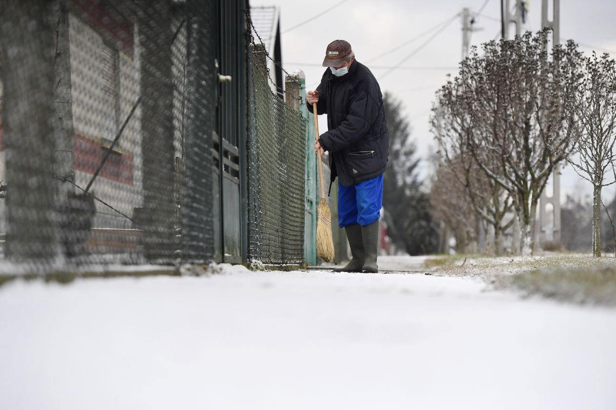 Havat takarít a járdáról egy férfi Gyálon 2020. január 14-én.