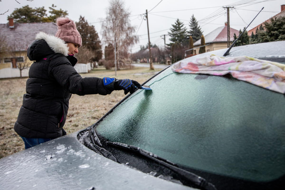 Egy nő takarítja az autóra fagyott ónos esőt a Békés megyei Gádoroson 2021. december 27-én.