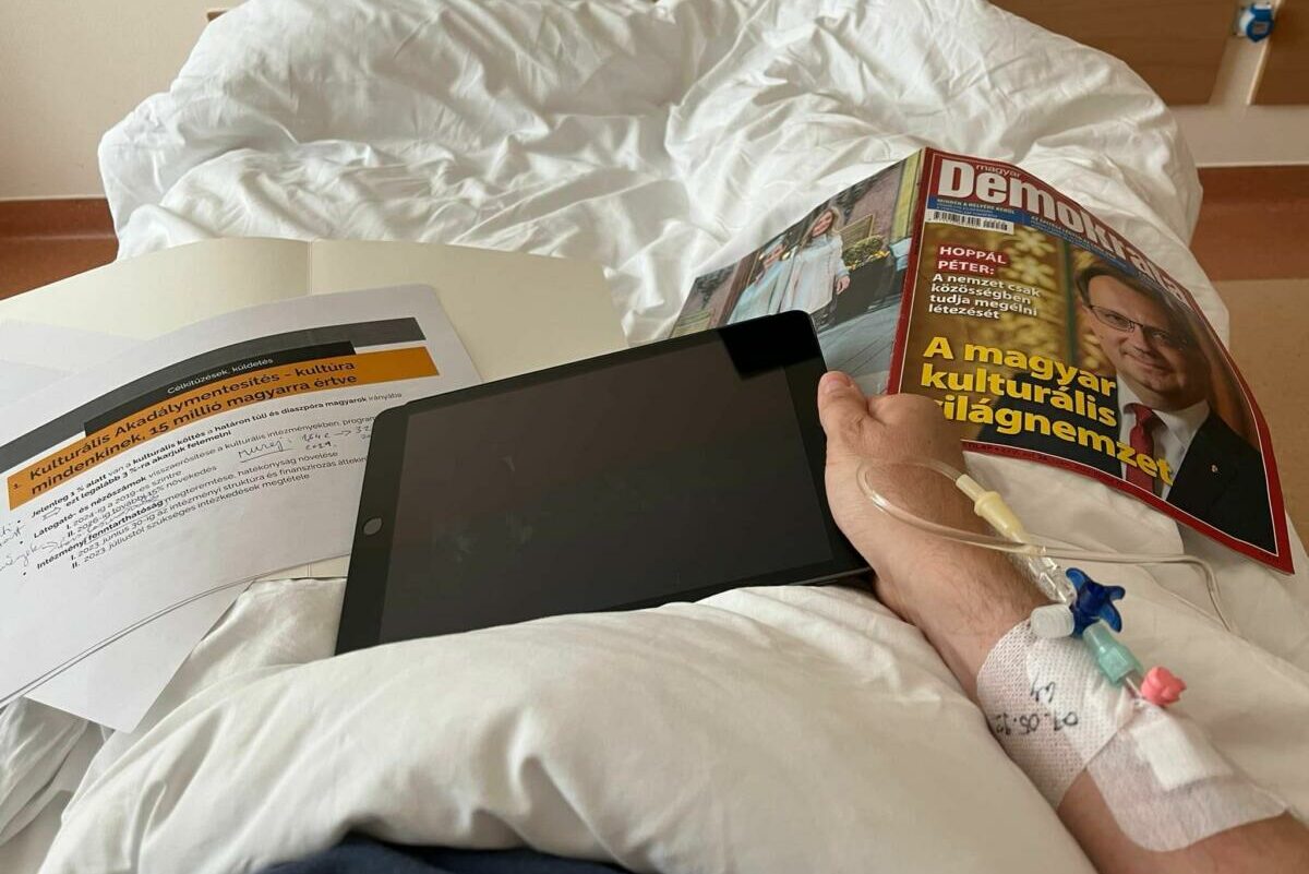 Hoppál Péter tablettel és egy önmagát ábrázoló újságcímlappal lábadozik.